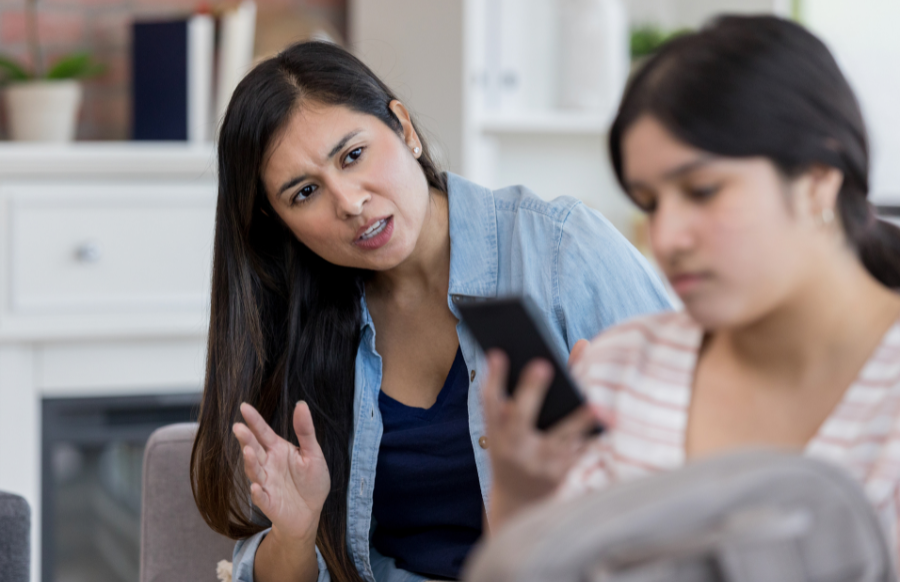 Mom talking to her daughter not listening by looking at her smart phone