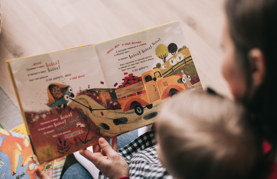 woman reading children's book to a baby