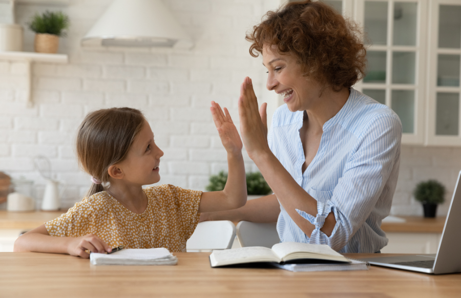 mother and daughter doing high five praising her child for doing homework
