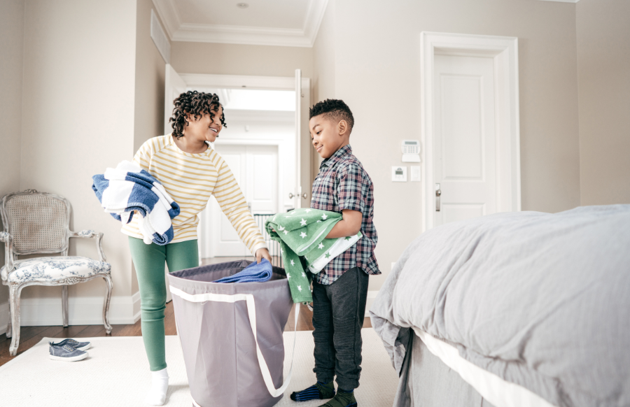 girl and boy putting folded clothes in the hamper