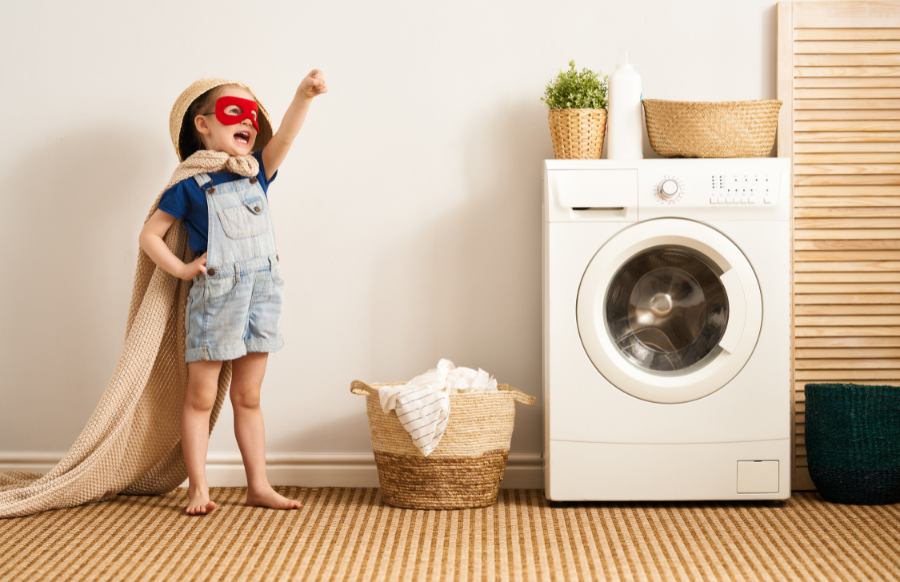 cute little girl is having fun and playing while doing the laundry.