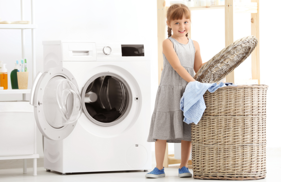 cute little girl doing laundy indoors