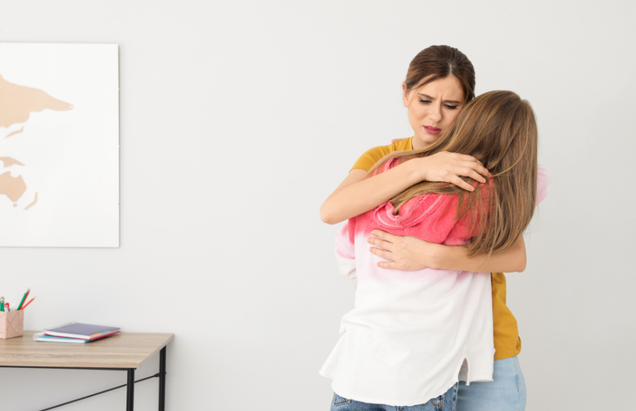 Mother hugging her teenage daughter at home